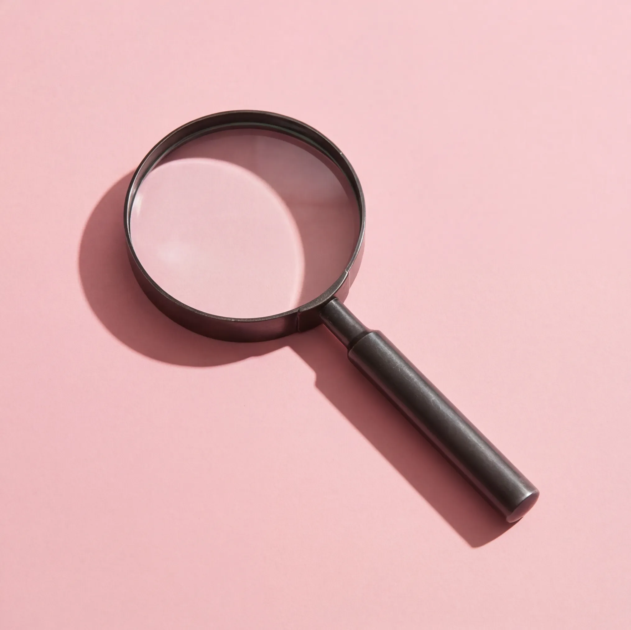 Magnifying glass on pink background representing AI-powered image search