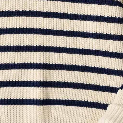 A close crop of the flat lay: navy stripes on a cream rib-knit sweater.