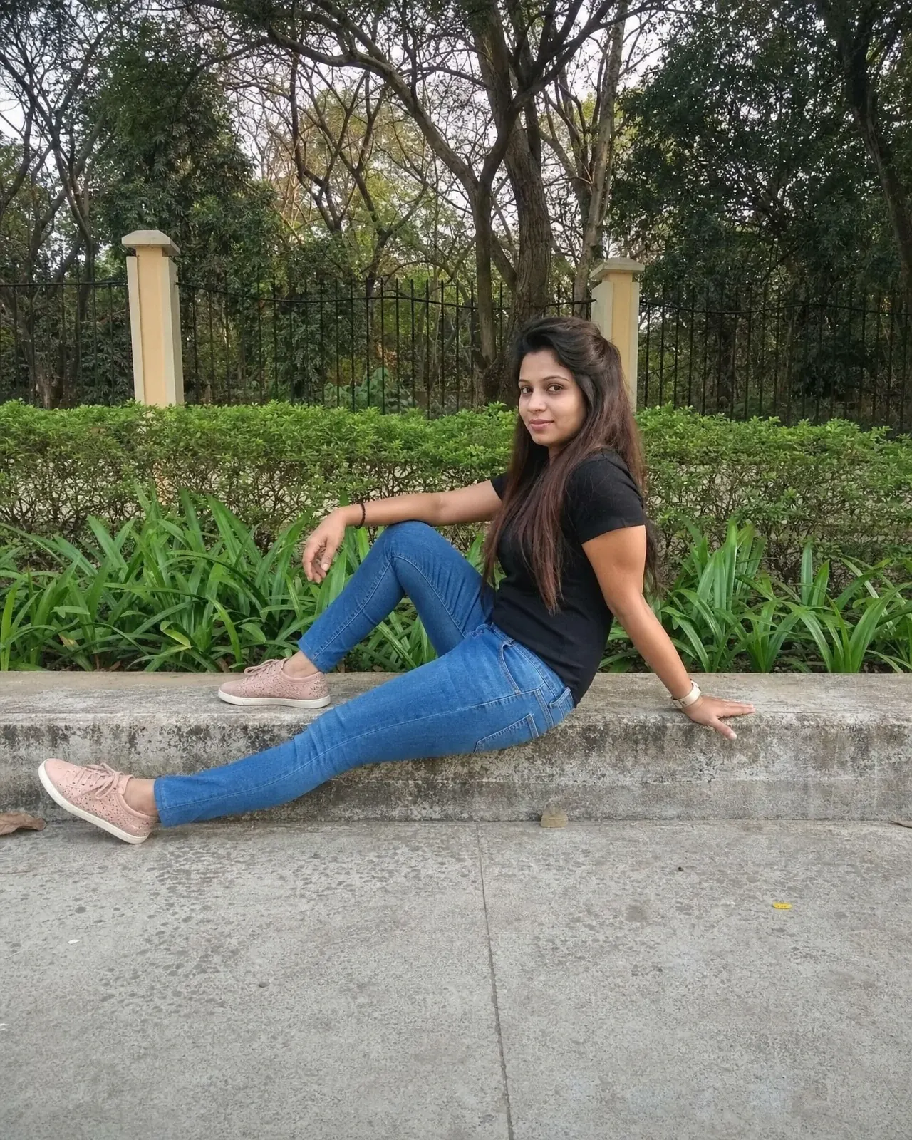 A casual photo of a woman seated on a park ledge, used only as a pose reference.
